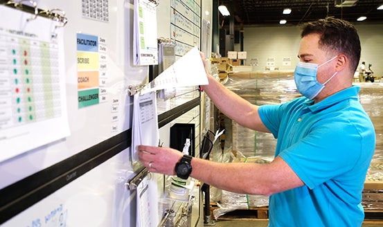 a man in a blue shirt and a face mask working on a white board