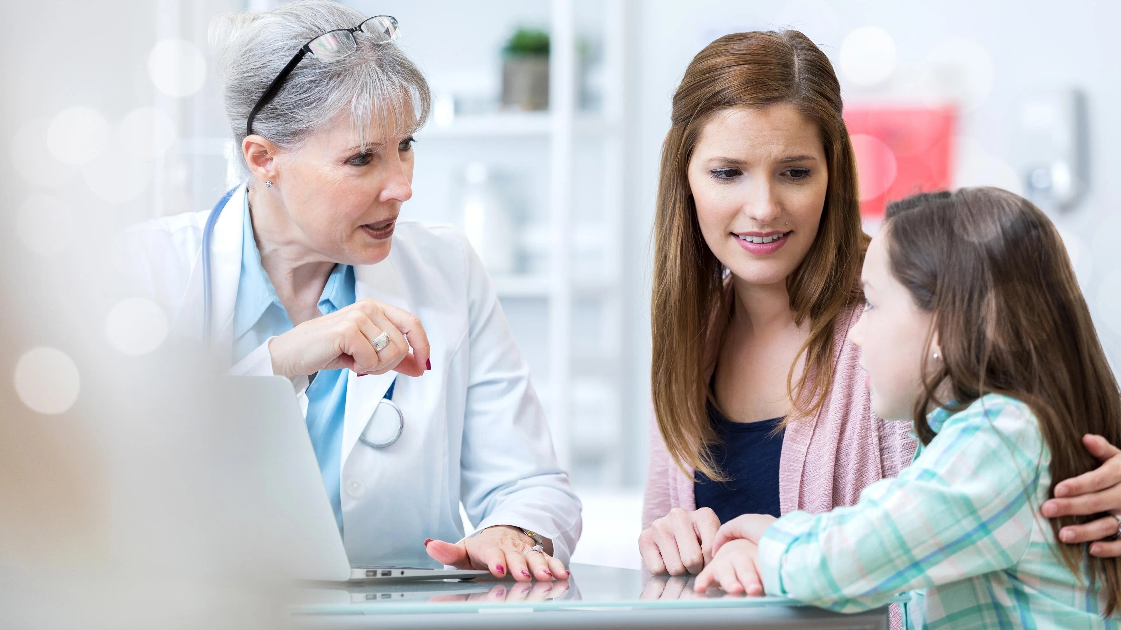 An Image of health care professional siting with a mother and her child discussing about Cystic Fibrosis